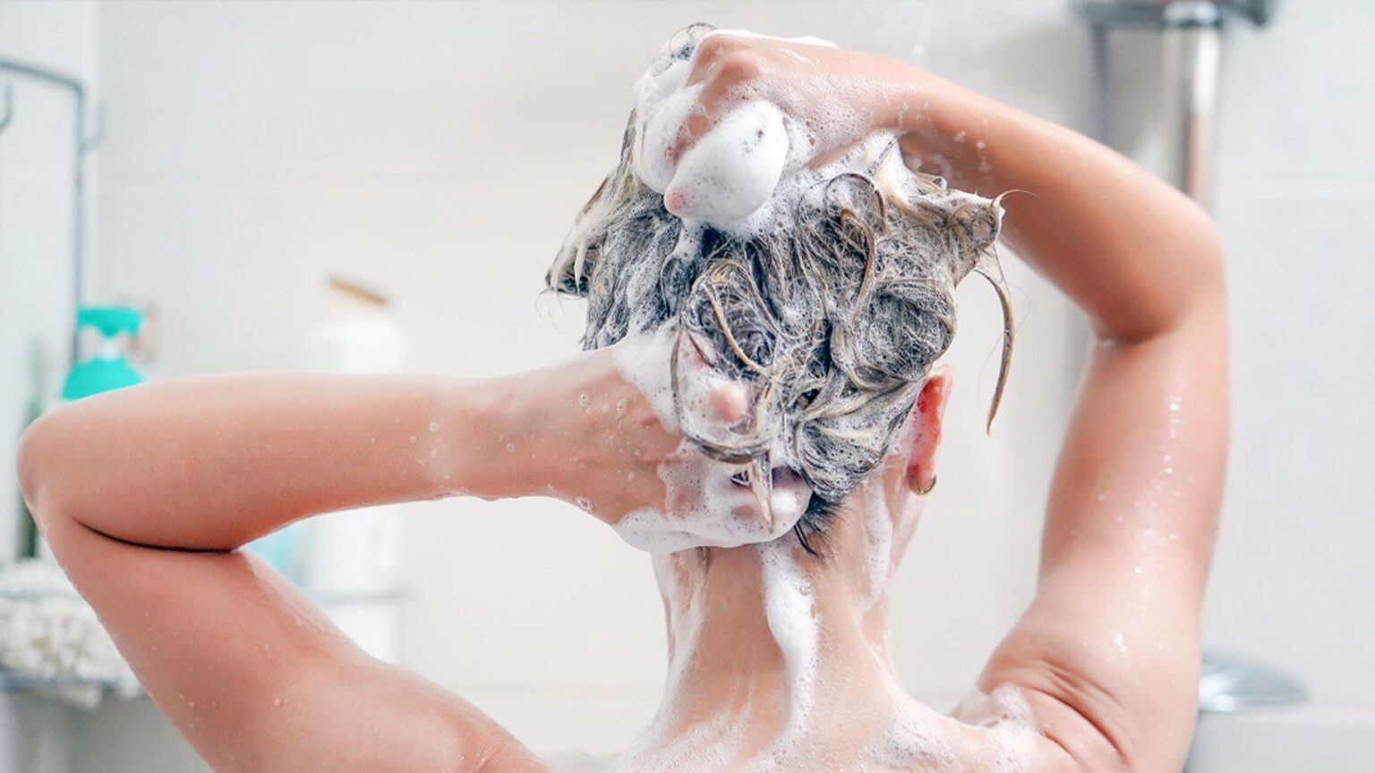 ragazza di insapona i capelli sotto la doccia