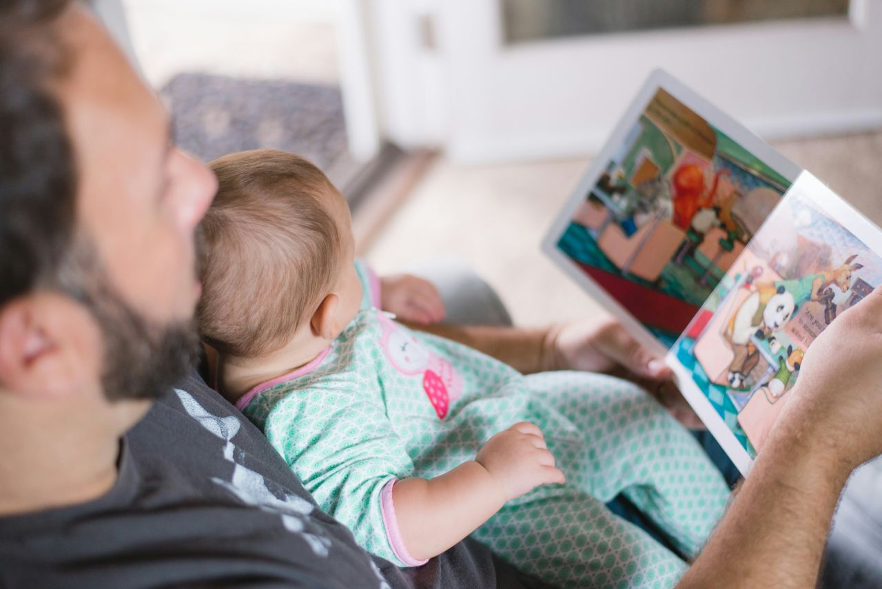 Papà con bimbo e libro di favole (fonte: Unsplash)