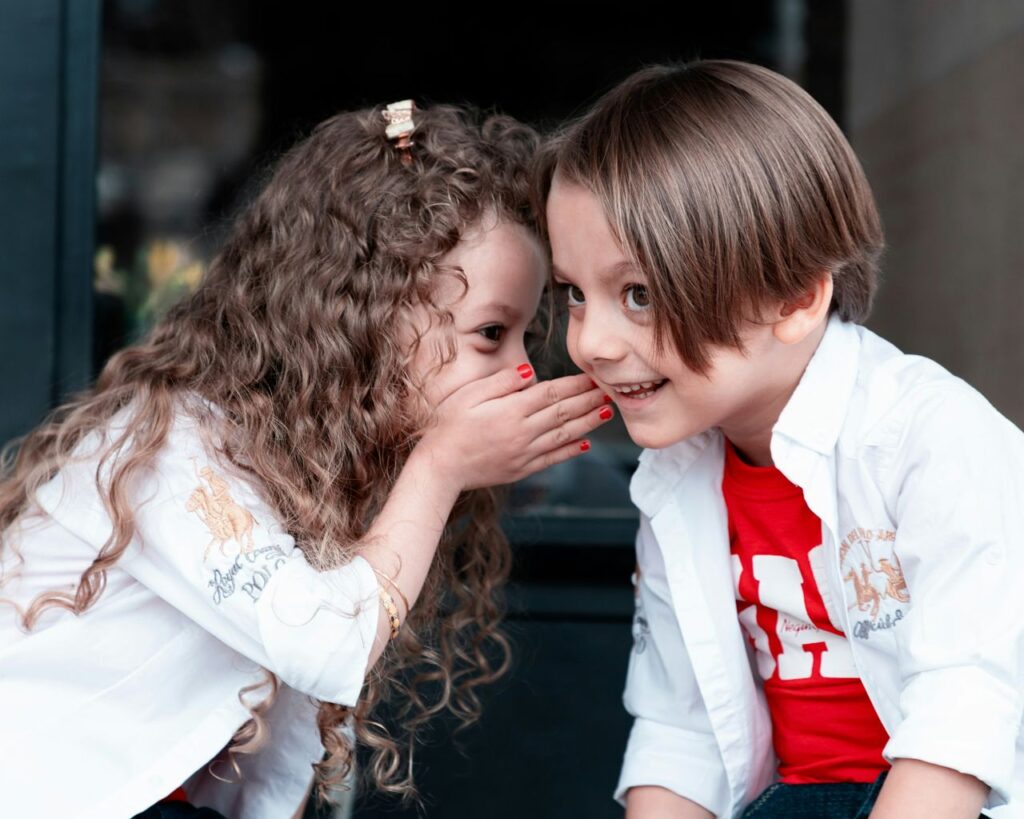 una bambina sussurra un segreto a un amico