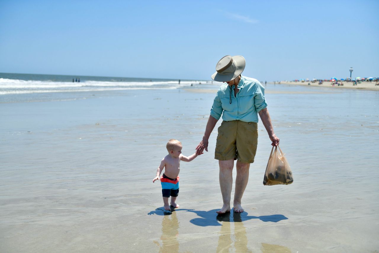 Una nonna a passeggio col nipotino sul bagnasciuga di una spiaggia