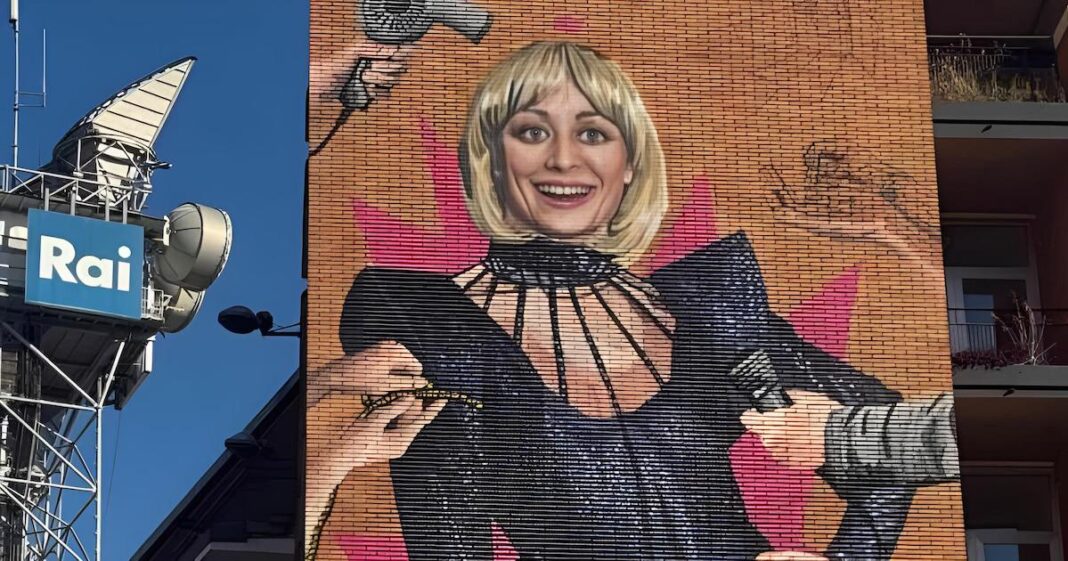 Il Murale che ritrae Raffaella Carrà con un. costume dis cena nero, il suo caschetto biondo e delle mani che la stanno preparando per lo show