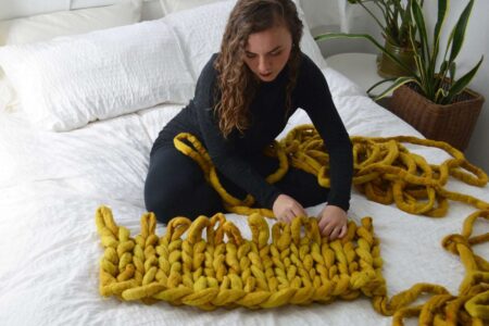 Ragazza fa una coperta con l'arm knitting