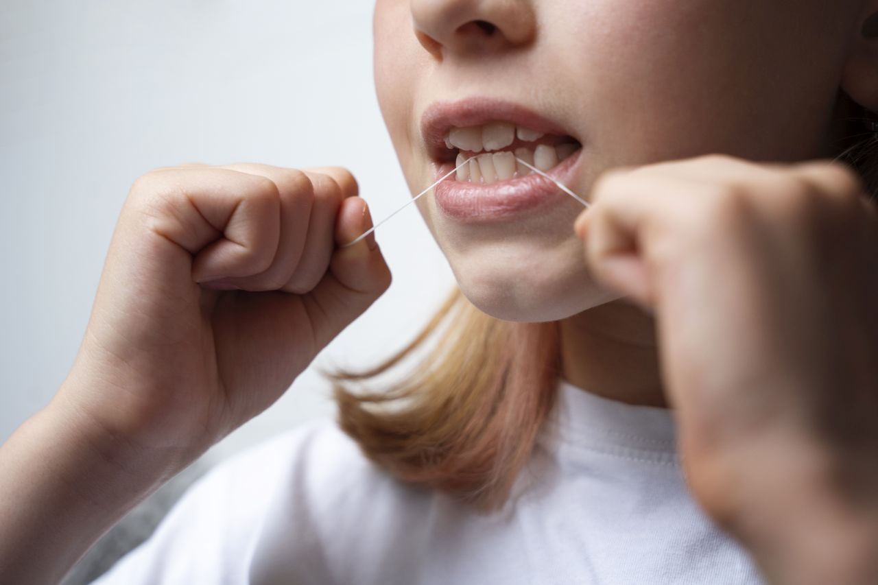 bambina che pulisce i denti con il filo