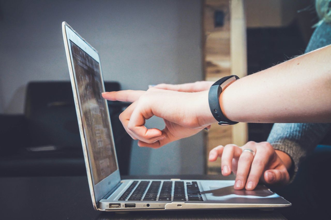 due persone lavorano davanti a un laptop puntando la mano verso lo schermo