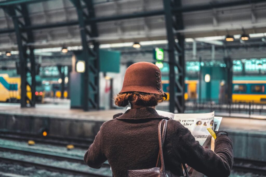 donna che legge giornale alla stazione