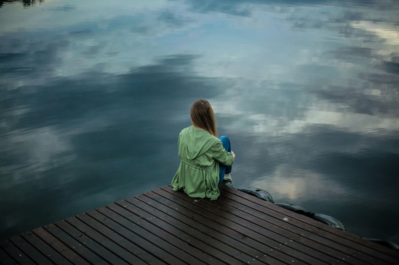 donna da sola che contempla un lago