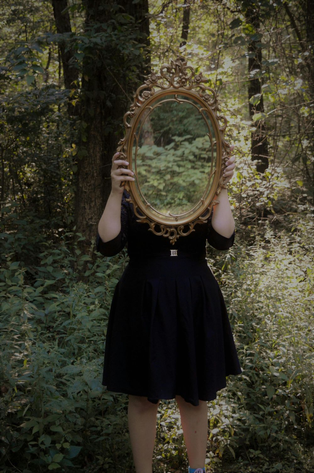 ragazza solleva specchio nel bosco