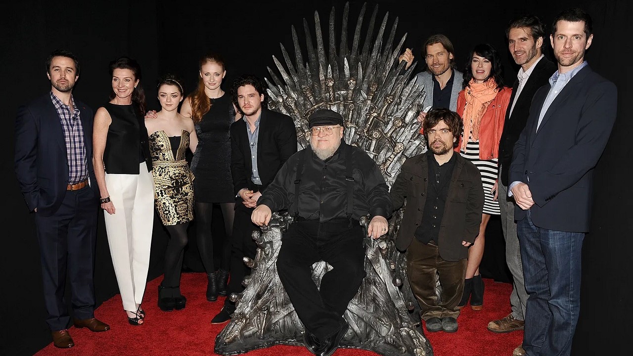 George R.R. Martin, autore delle "Cronache del Ghiaccio e del Fuoco", posa sul trono di spade insieme ad alcuni membri del cast della serie