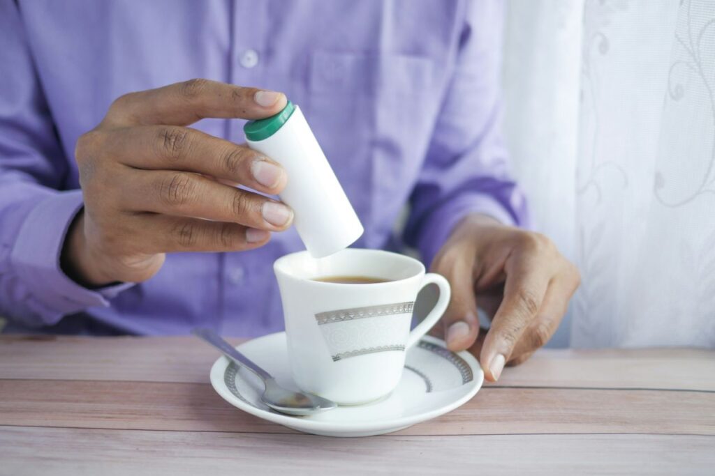 persona mette dolcificante nel caffè