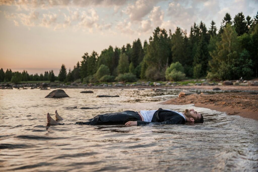 persona sdraiata sulla riva di un lago