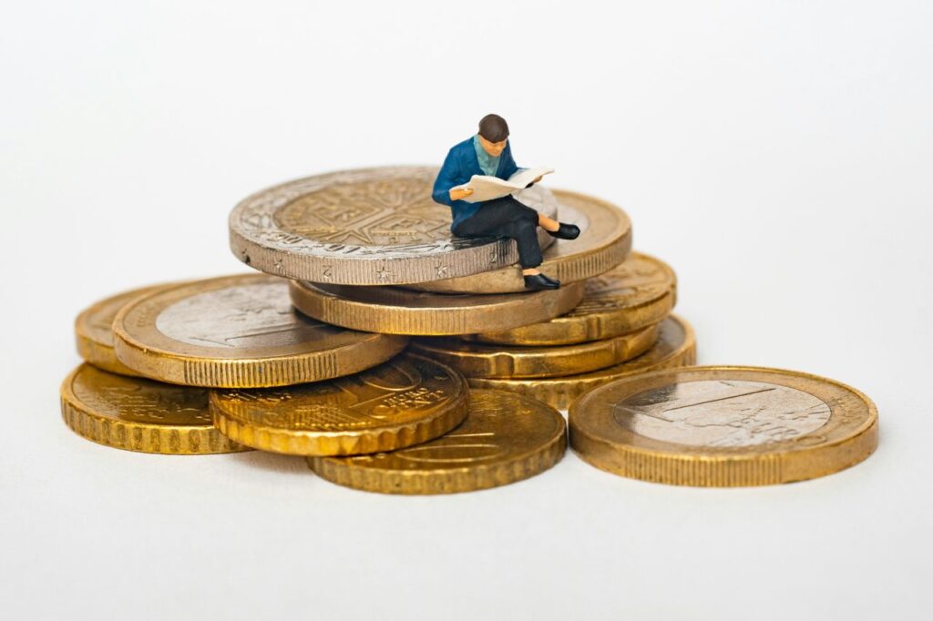 persona in miniatura seduta su monete Euro