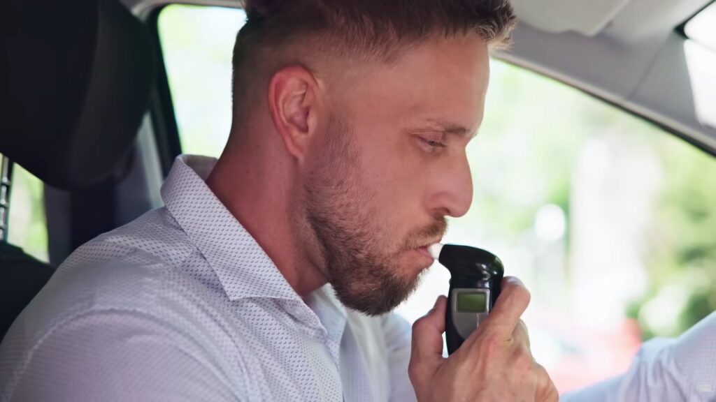 Un automobilista soffia su un alcolock prima di mettersi alla guida