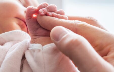 Un neonato stringe il dito di suo padre